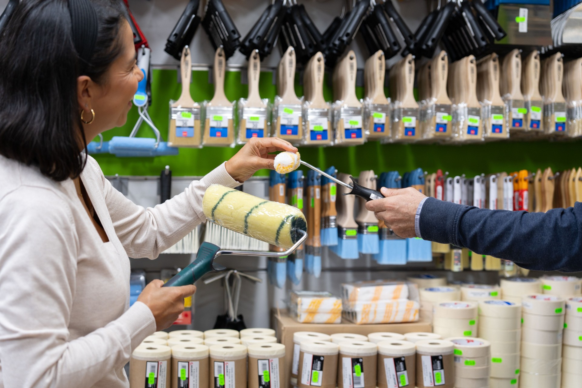 woman being advised in paint store to choose tools to paint and decorate her house